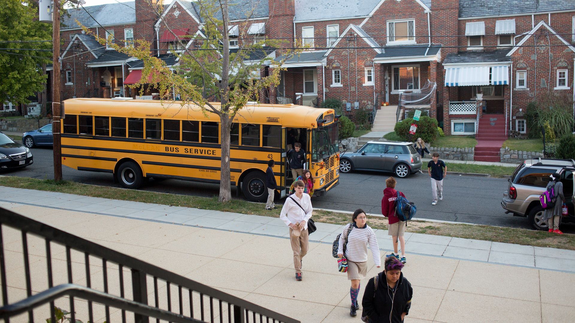 Students getting off of a school bus and heading into the school building.