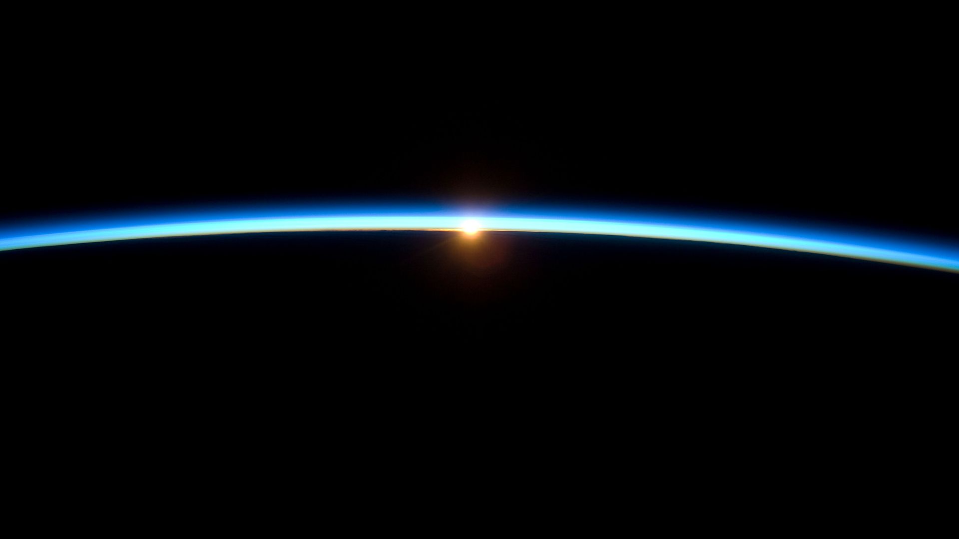 The thin line of Earth's atmosphere and the setting sun seen from the International Space Station.