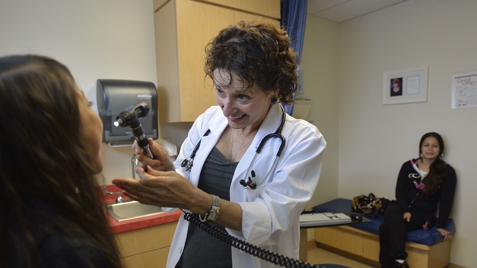 A doctor examines a patient in a medical clinic room.