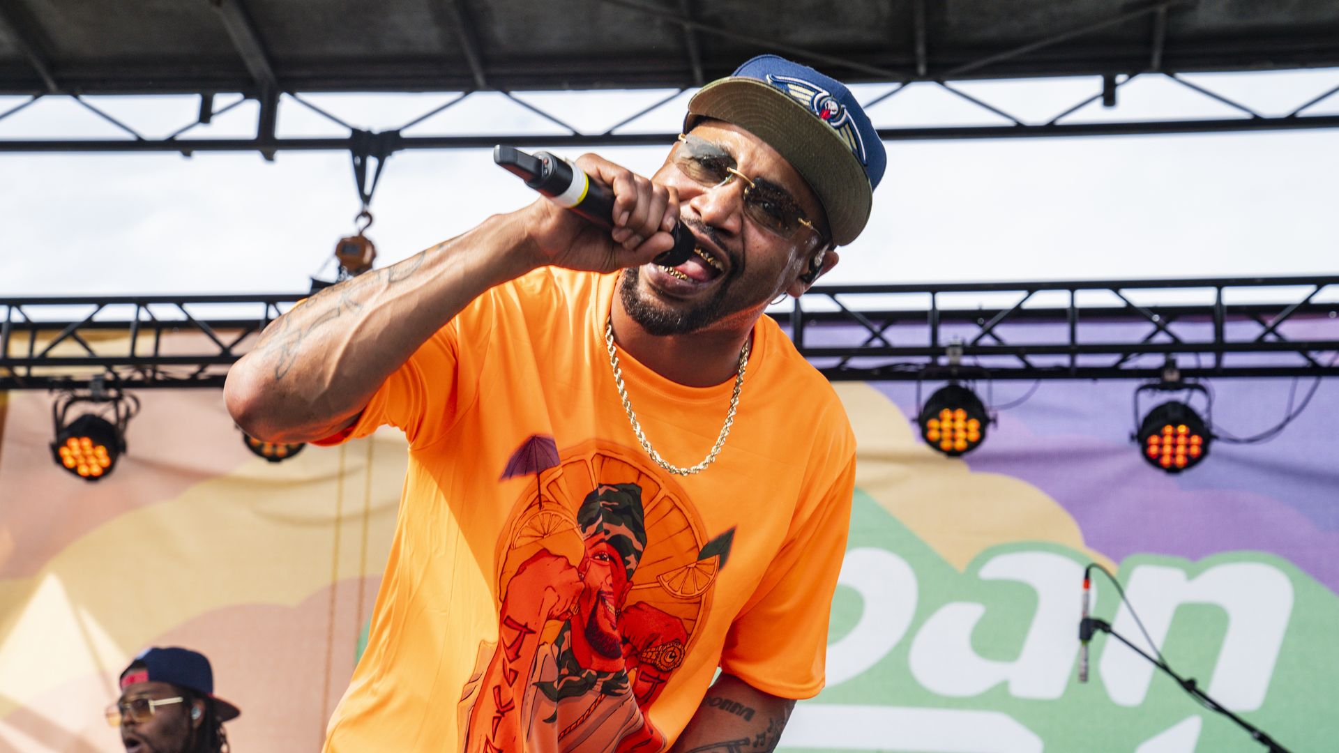 A rapper holding a microphone to his face on a stage.