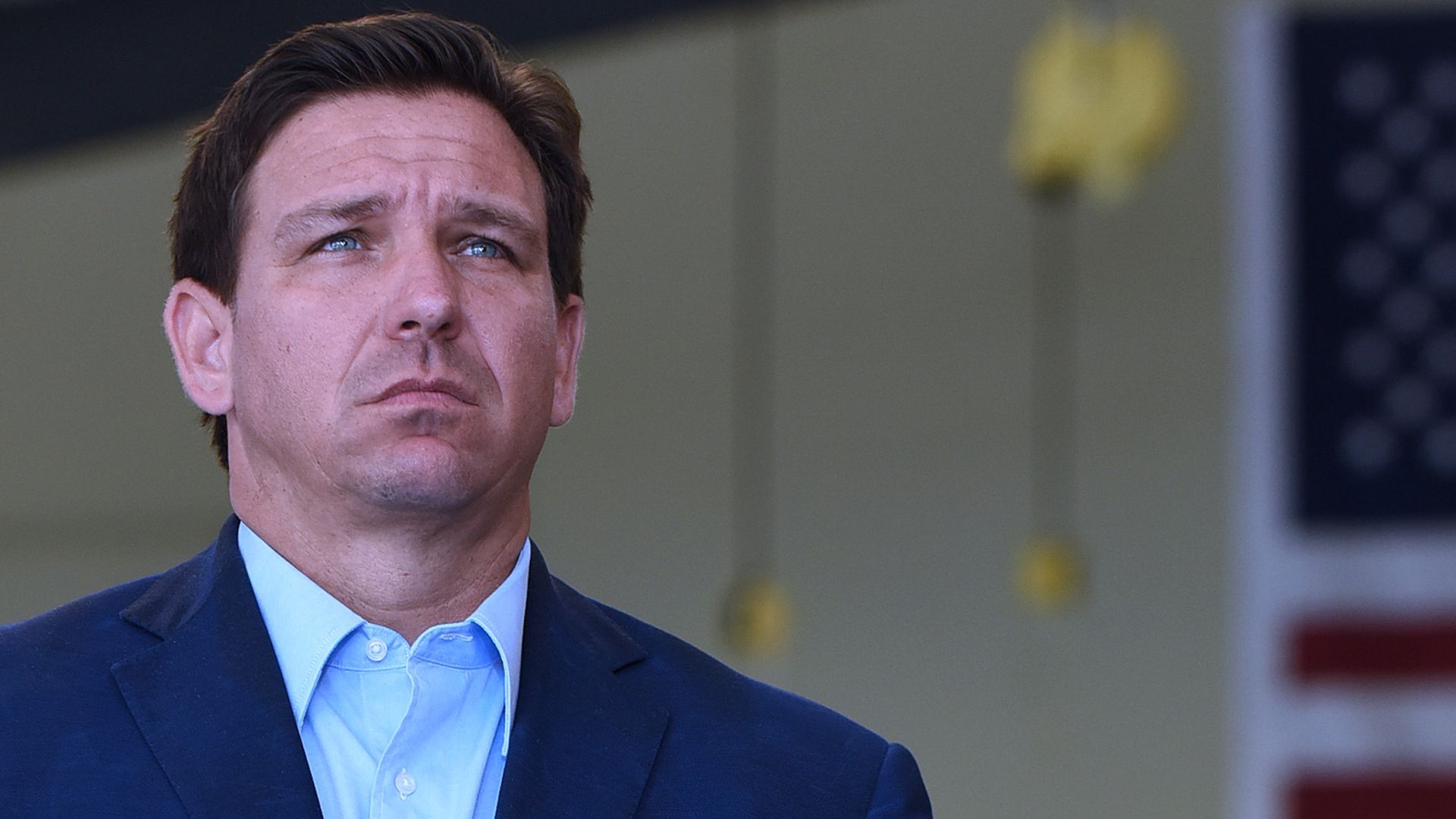 Florida Governor, Ron DeSantis listens to another speaker at a press conference at the Eau Gallie High School aviation hangar.