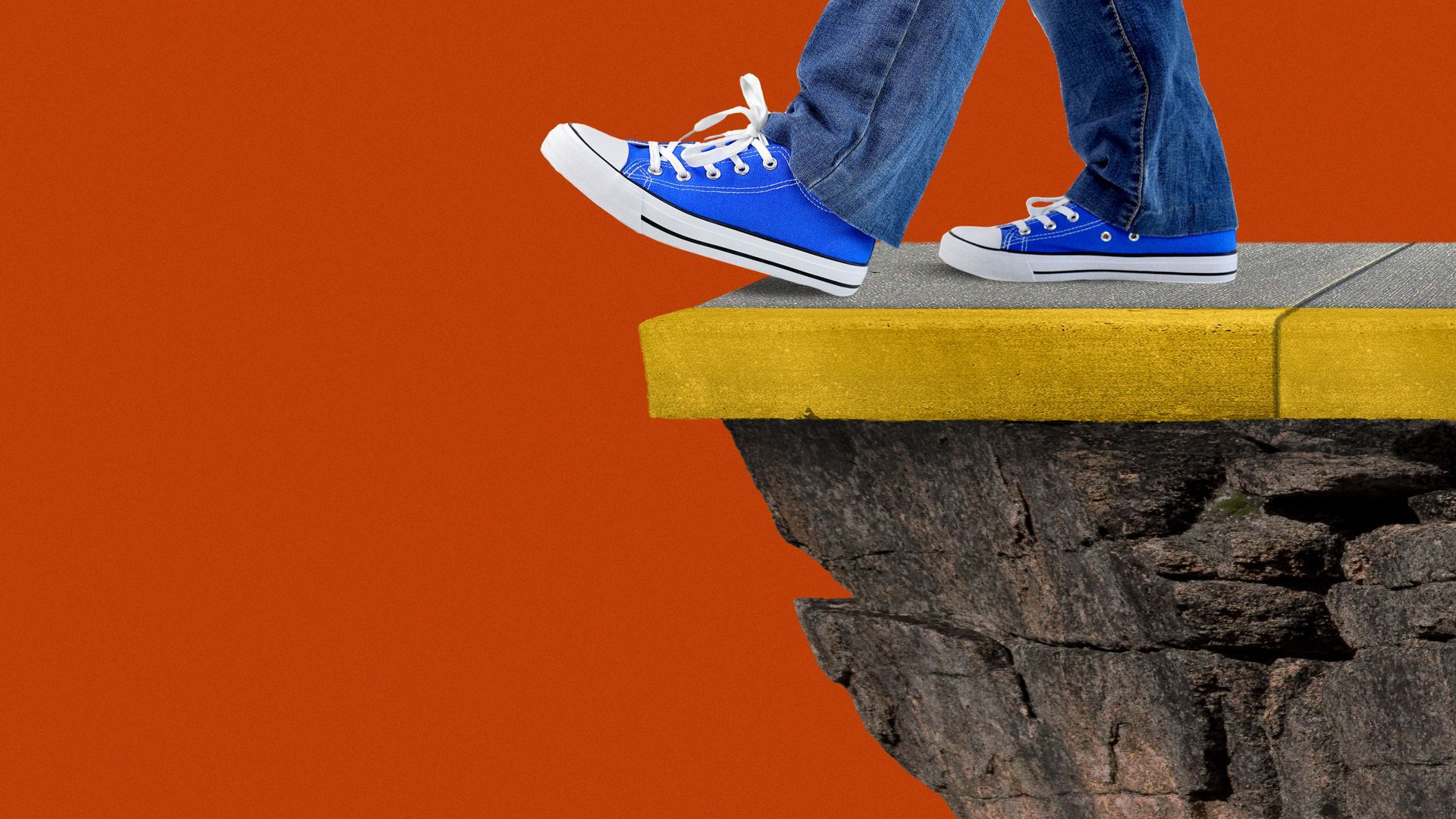 A close-up of someone's feet nearing the edge of a sidewalk on a cliff.