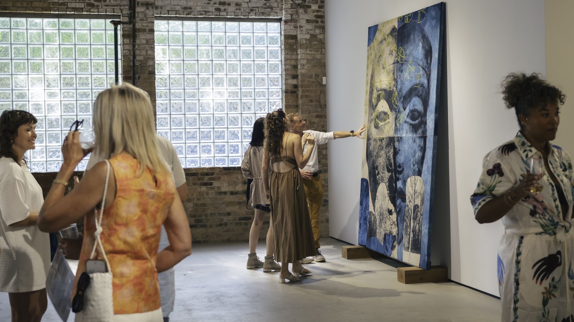 People standing in an art gallery talking, with one pointing to a large canvas.