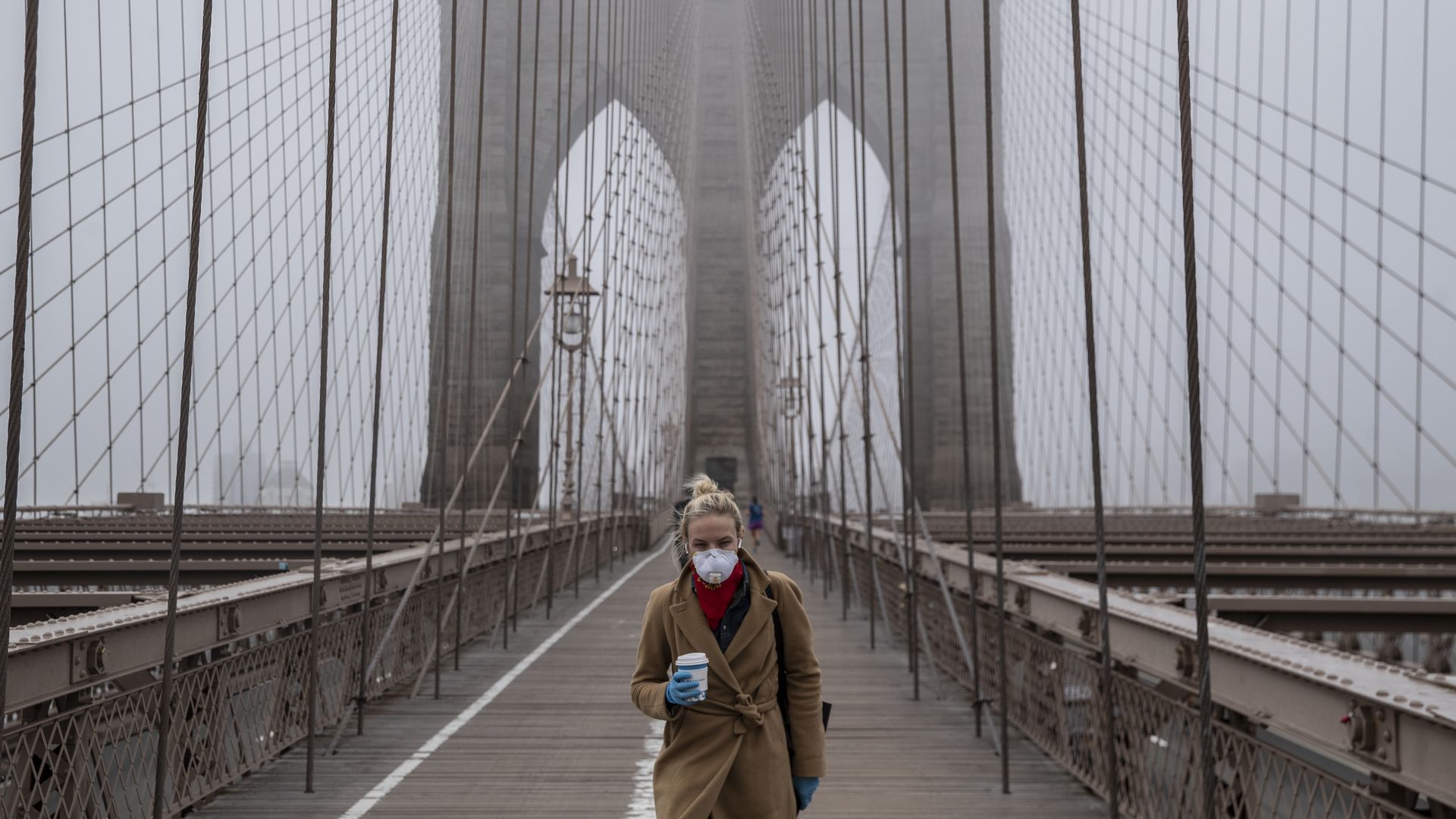 Woman with facemask walking on the Brooklyn Bridge.