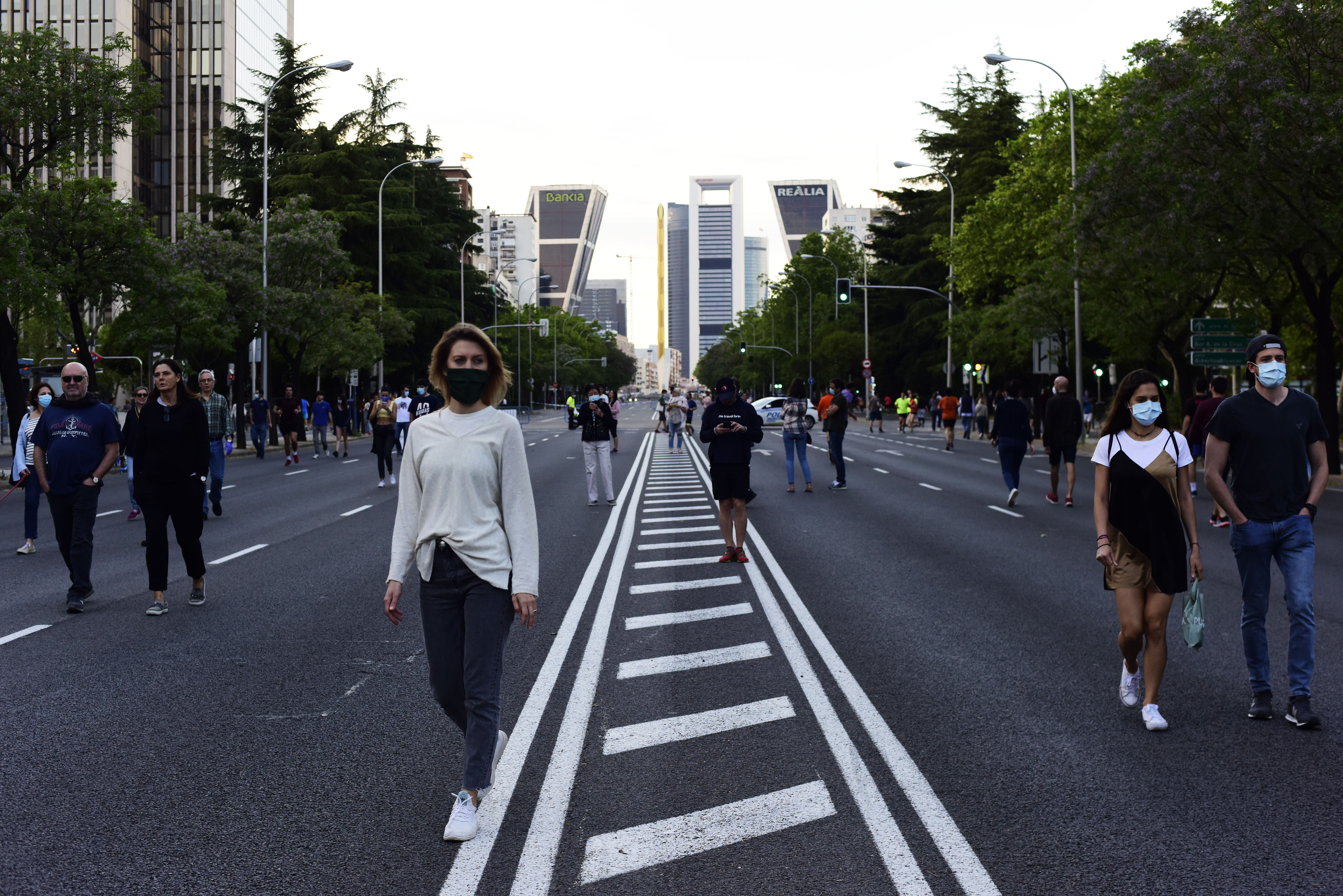People wearing face masks walk down Paseo de la Castellana street during the hours allowed on May 9