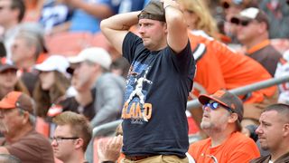 A Cleveland Browns fan stands with hands on his head in frustration.