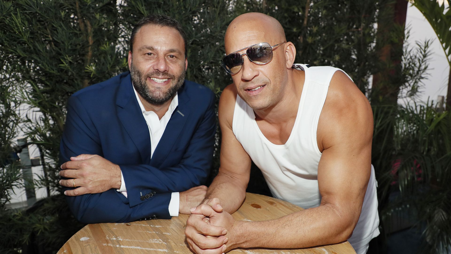 David Grutman poses wearing a blue suit with Vin Diesel in a white tank top.