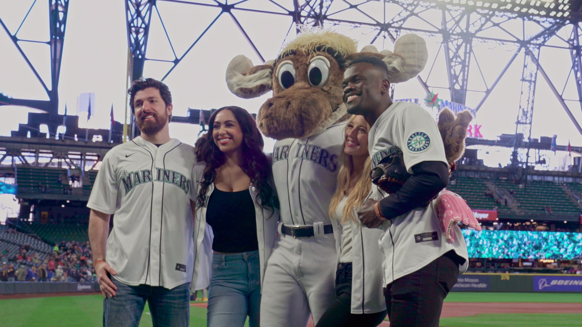 Two couples from "Love Is Blind" season 4 cast at a Seattle Mariners game posing with the Mariners mascot..