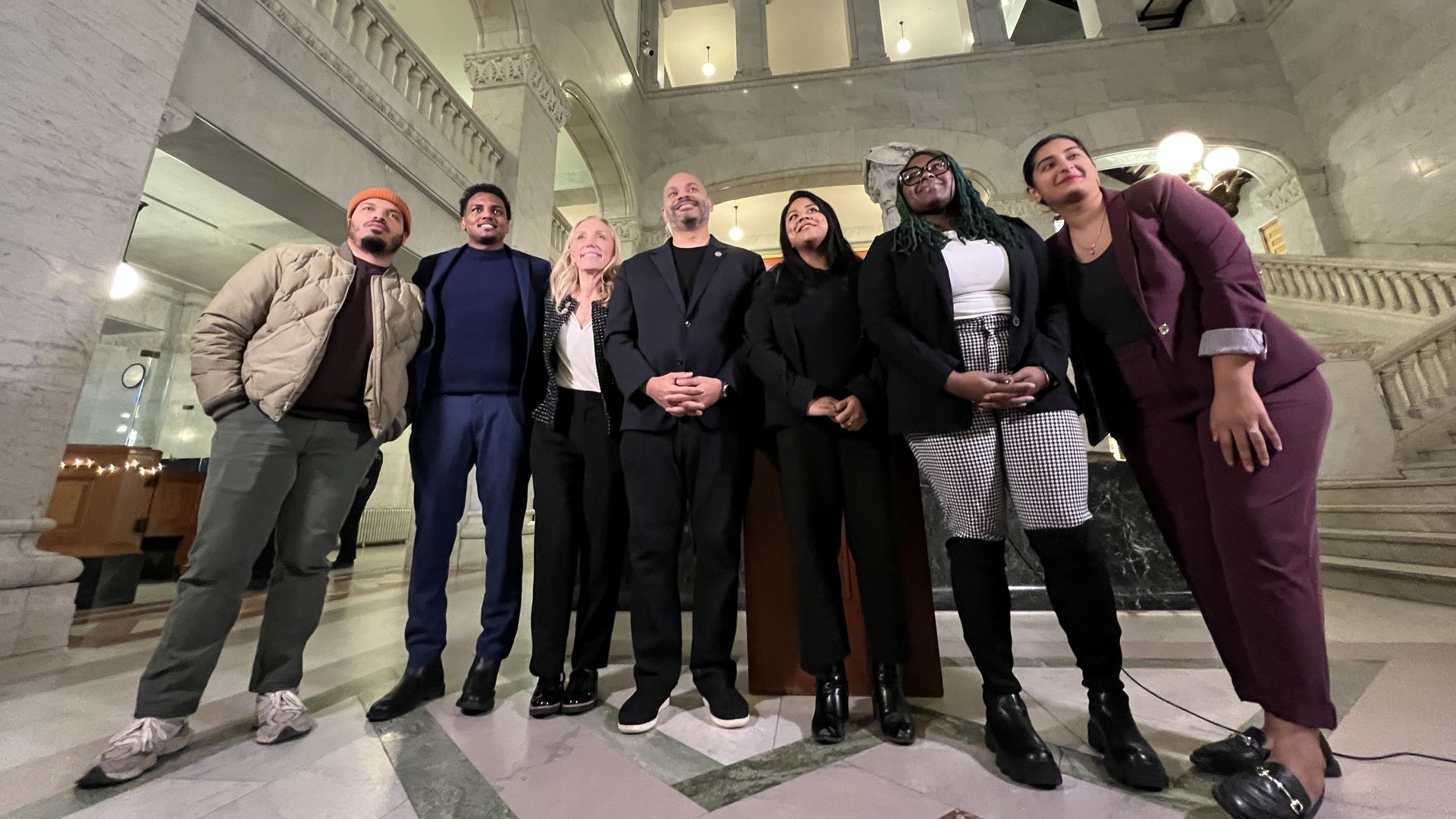 A group of people stand in a large marble hall