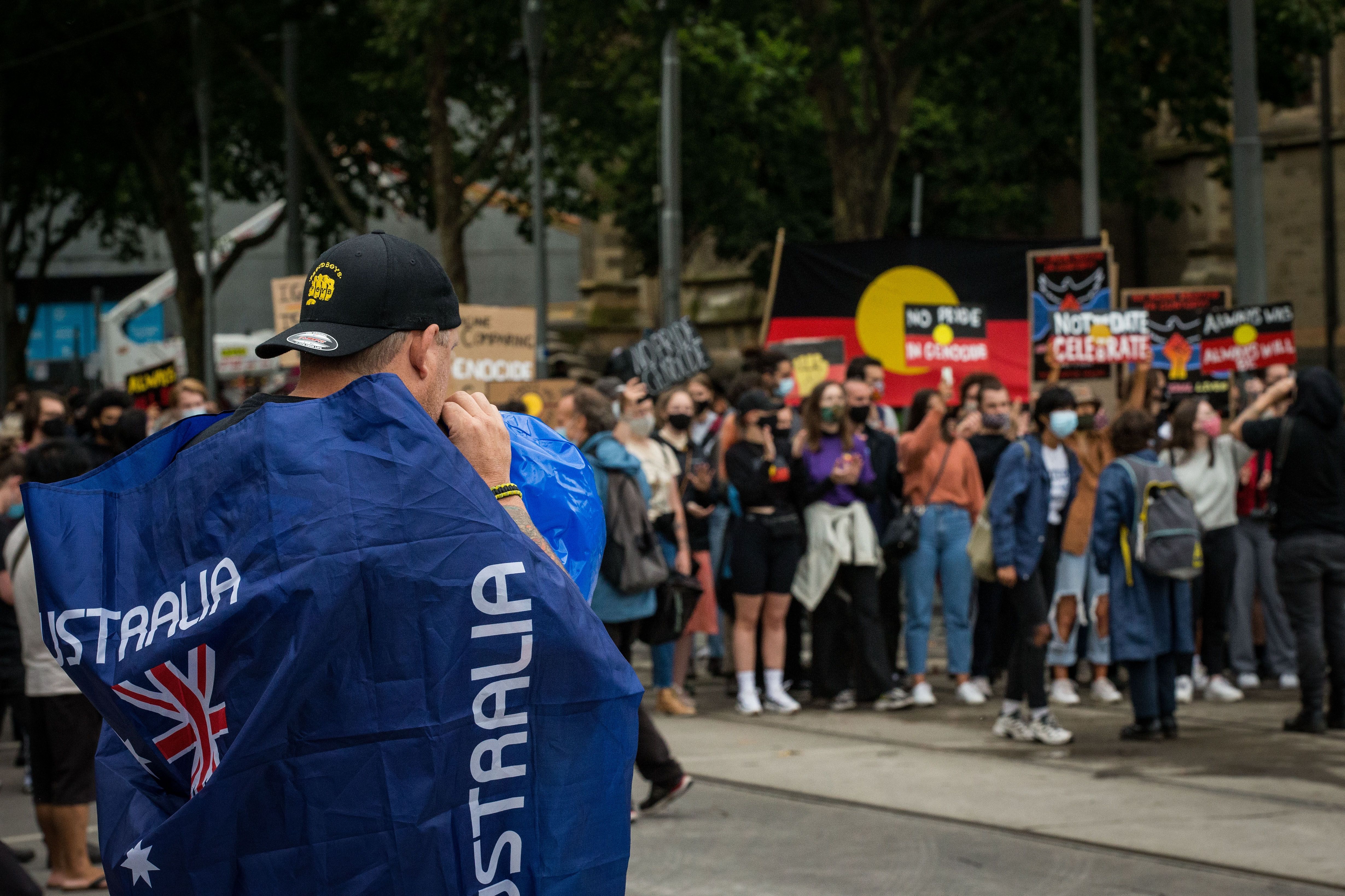 A man wearing a 'Proud Boys' shirt and an Australian flag attends the Invasion Day rally in the city on January 26, 2021 in Melbourne, Australia. 