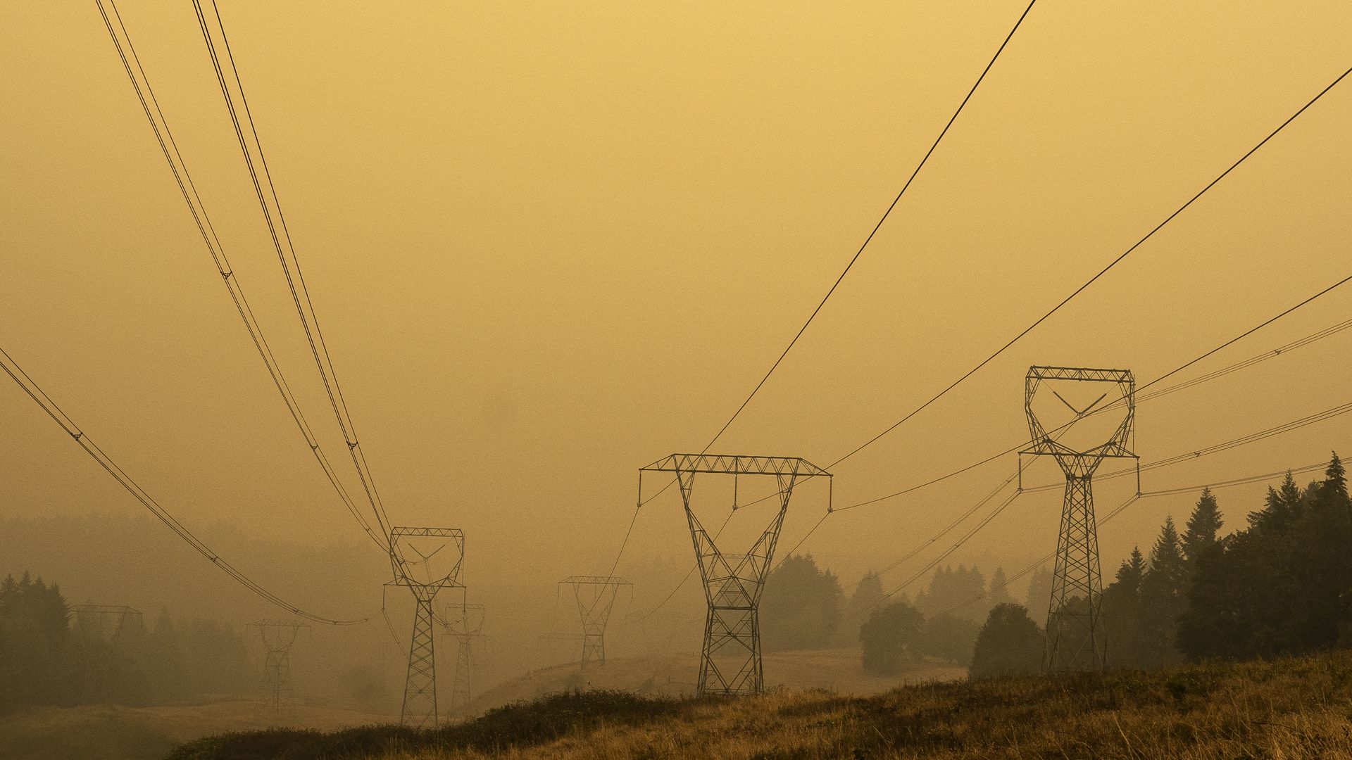 Electricity lines against a smokey yellow sky