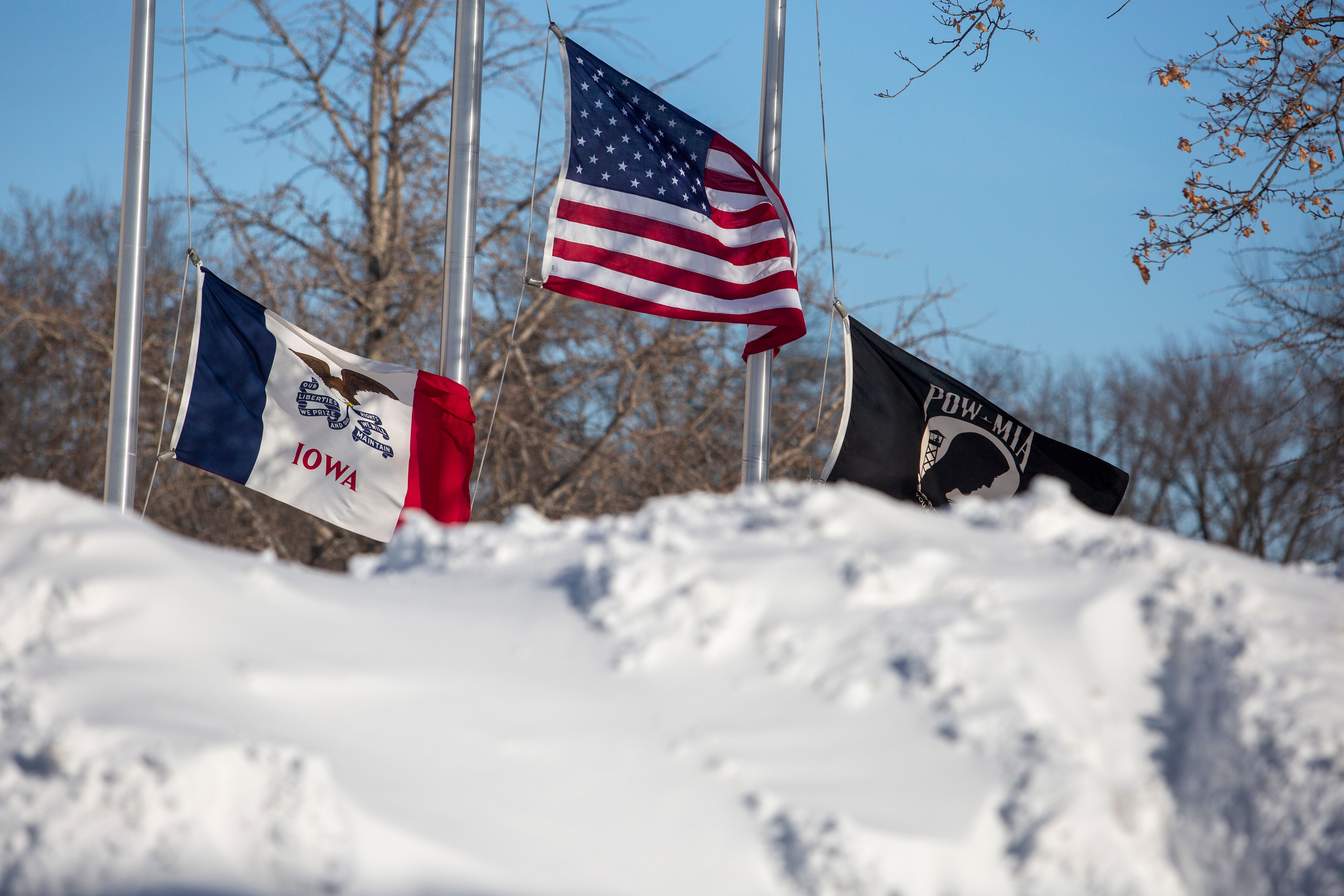 Flags surrounded by snow piles during a winter storm ahead of the Iowa caucus in Adel, Iowa, US, on Sunday, Jan. 14, 2024. Iowans on Monday will cast the first votes in the 2024 presidential nominating process during a caucus that's likely to show depressed turnout because of historically frigid weather.