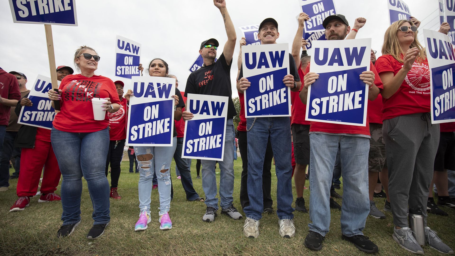 Workers hold picket signs supporting the UAW strike