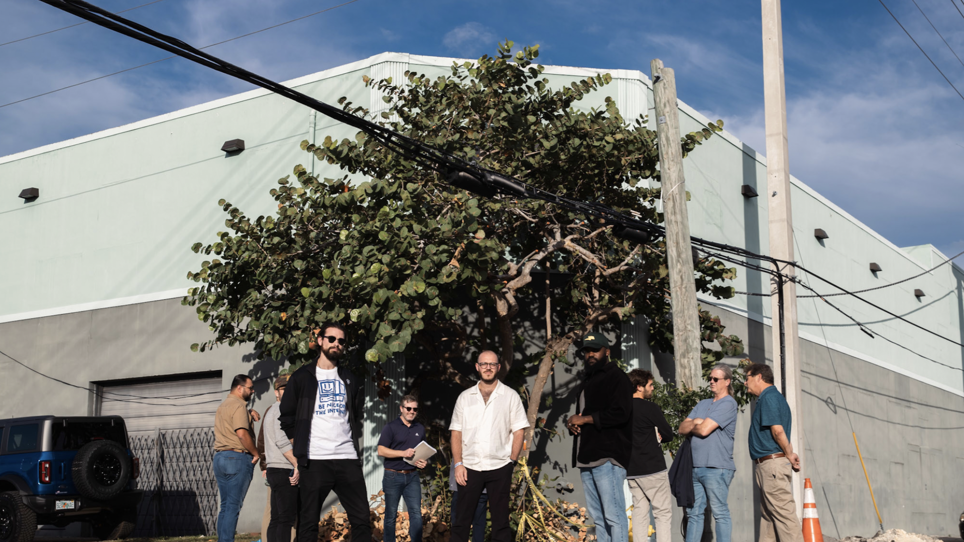 Men in front of an industrial building on a sunny day. 