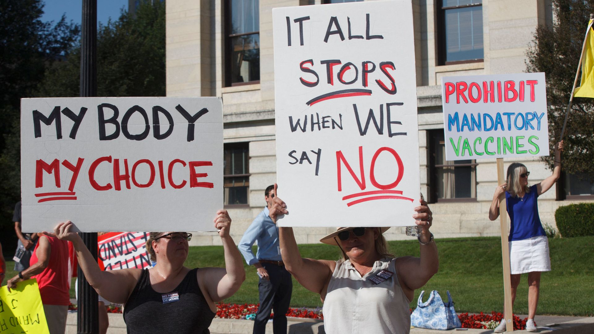 Anti-vaccine demonstrators hold signs outside the Ohio Statehouse.