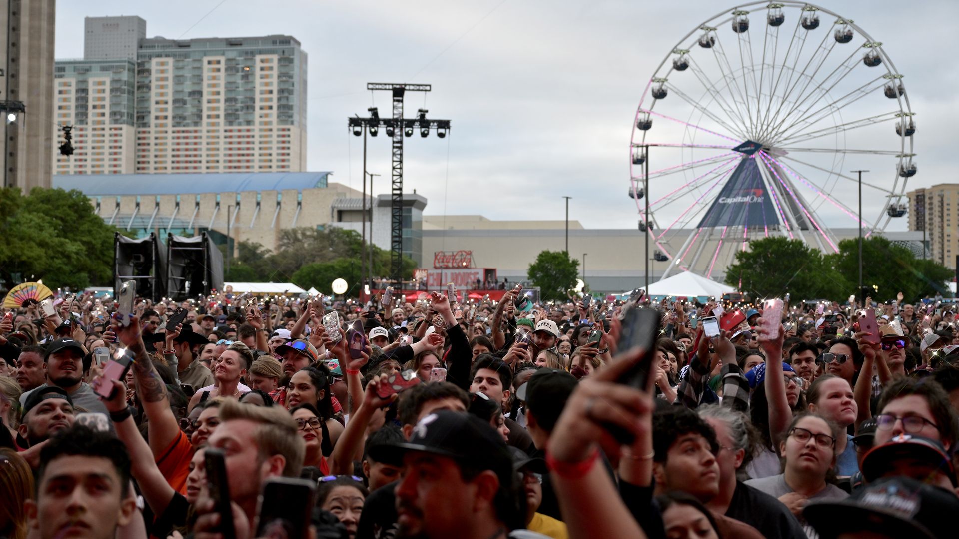 A view of the crowd at the March Madness Music Festival with the ferris wheel and Grand Hyatt hotel in the background.