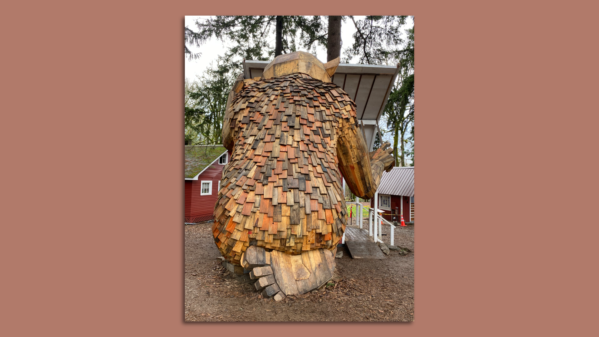 The back of a giant wooden troll is seen, kneeling and sitting on his foot.