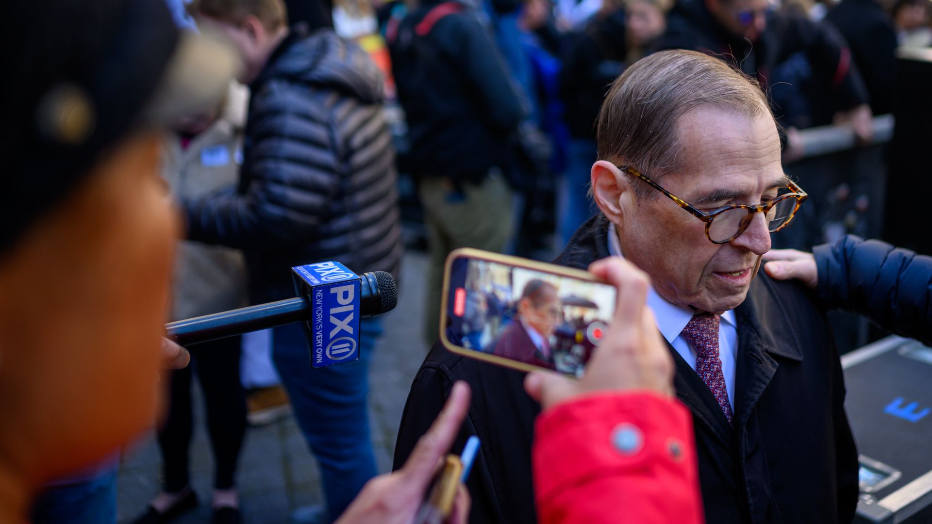 House Judiciary Committee Ranking Member Jerrold Nadler, wearing a black overcoat, light blue shirt and purple tie, being filmed outside by reporters.