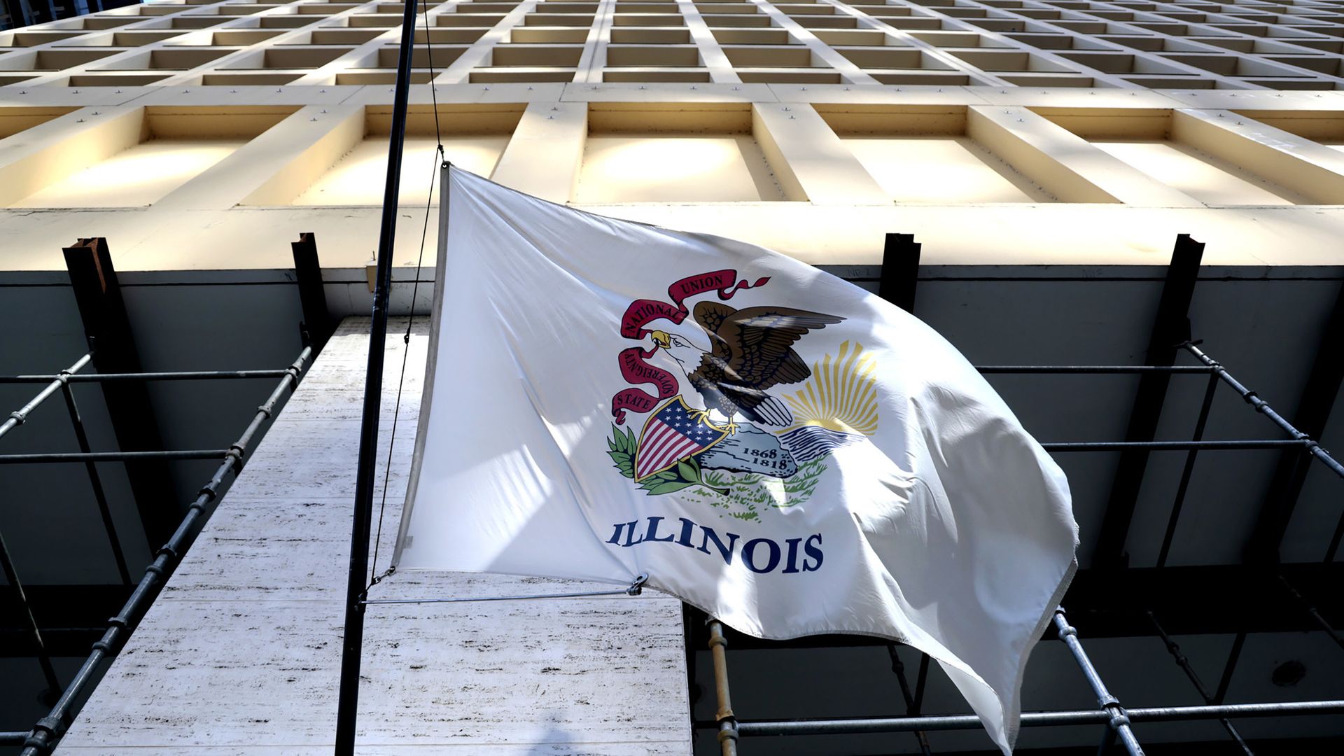 The state flag of Illinois waves outside of a downtown Chicago building.