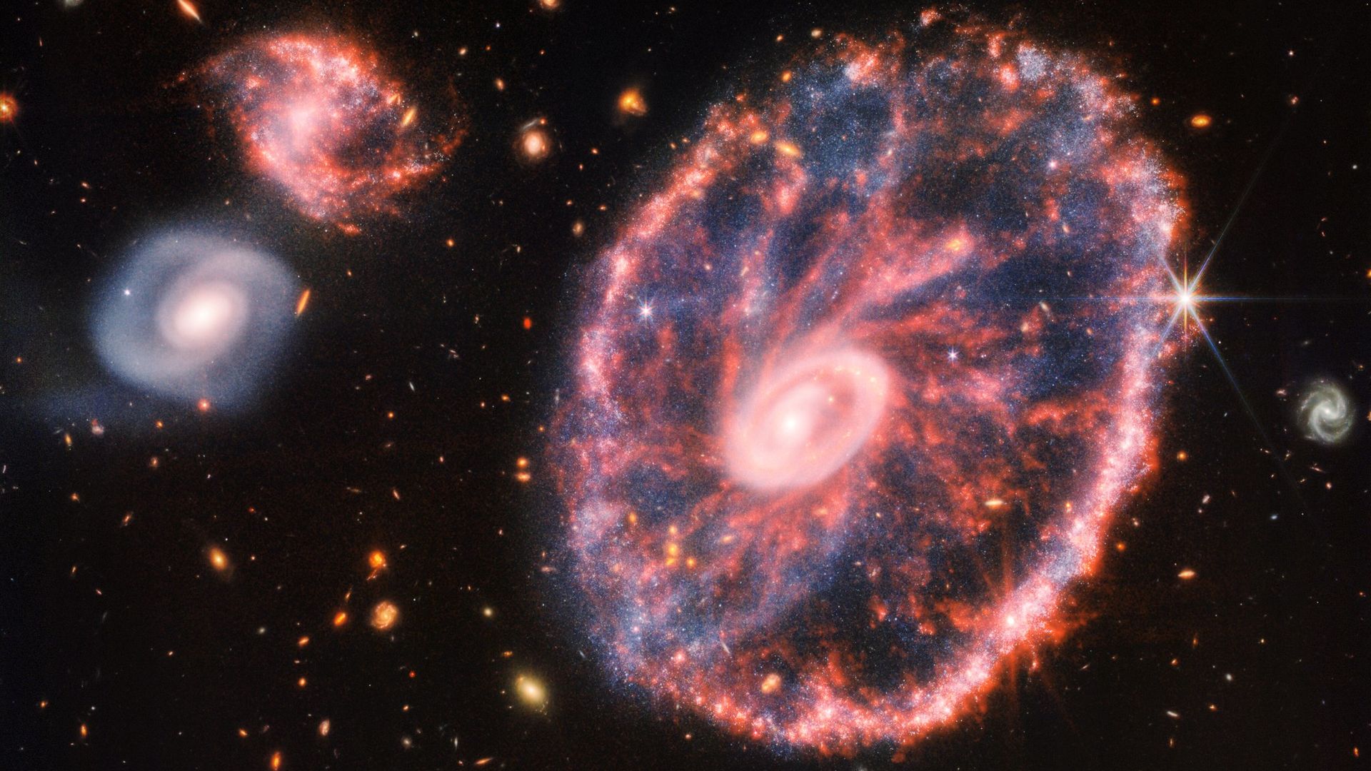 A galaxy shining in pink and blue seen by the JWST.