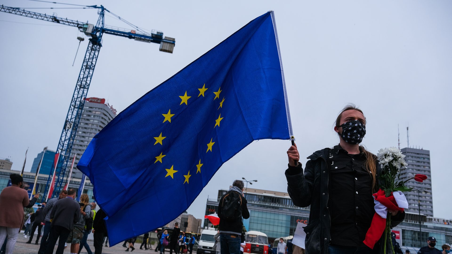 A masked woman holds the European Union flag