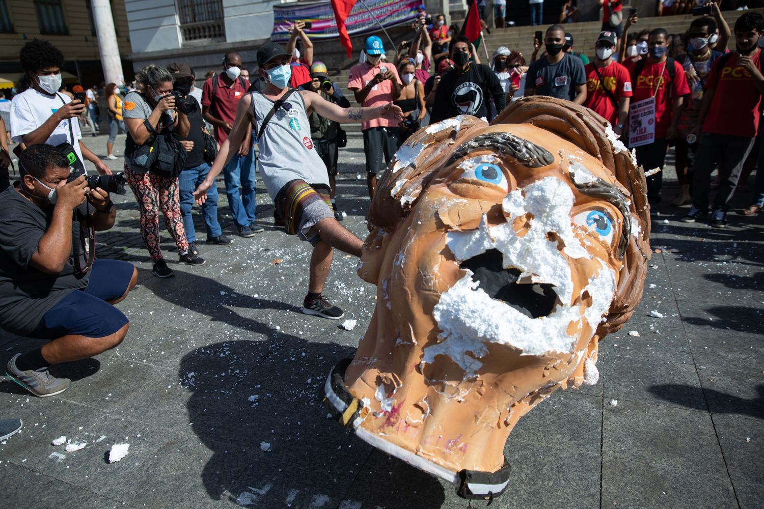 A protester kicks a papier mache head meant to represent Brazilian President Bolsonaro. 