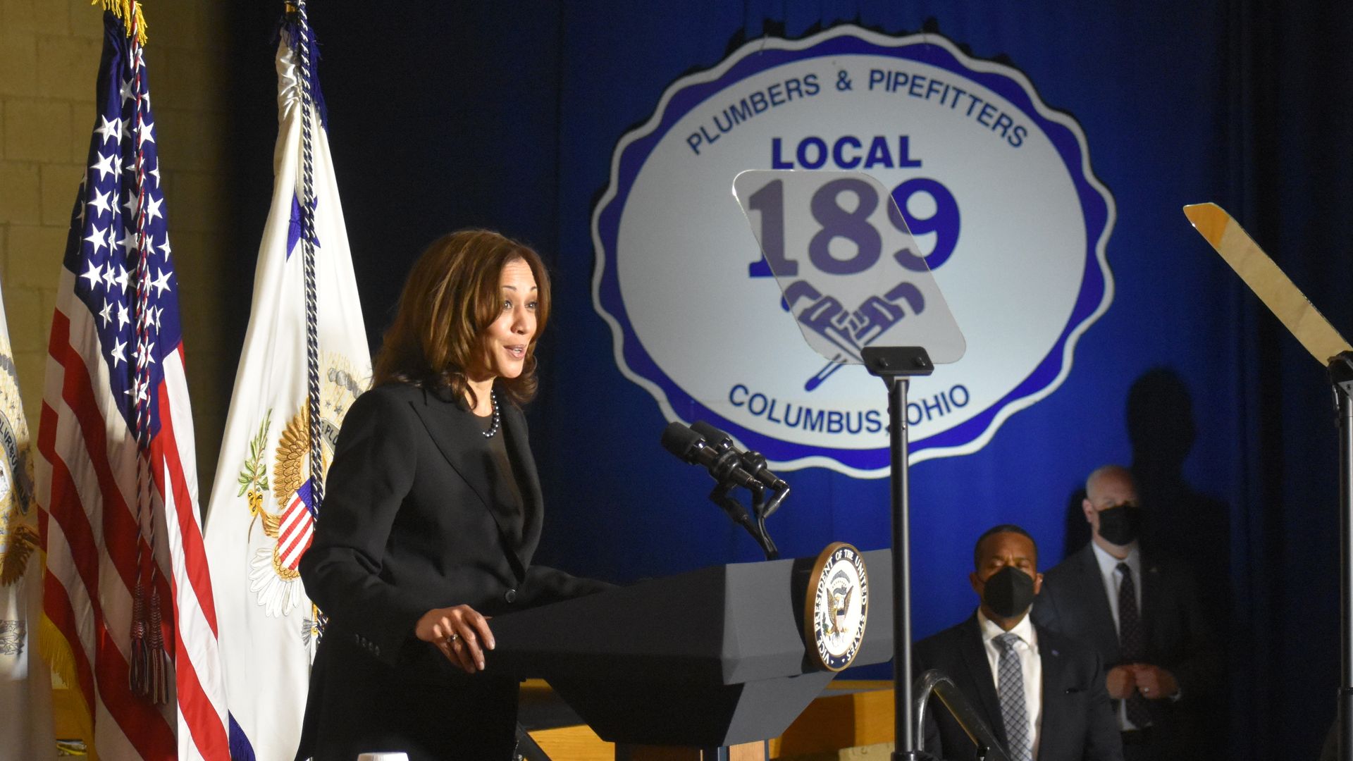 Vice President Kamala Harris speaks at a Columbus union hall with a large display of the union's logo on the side wall.