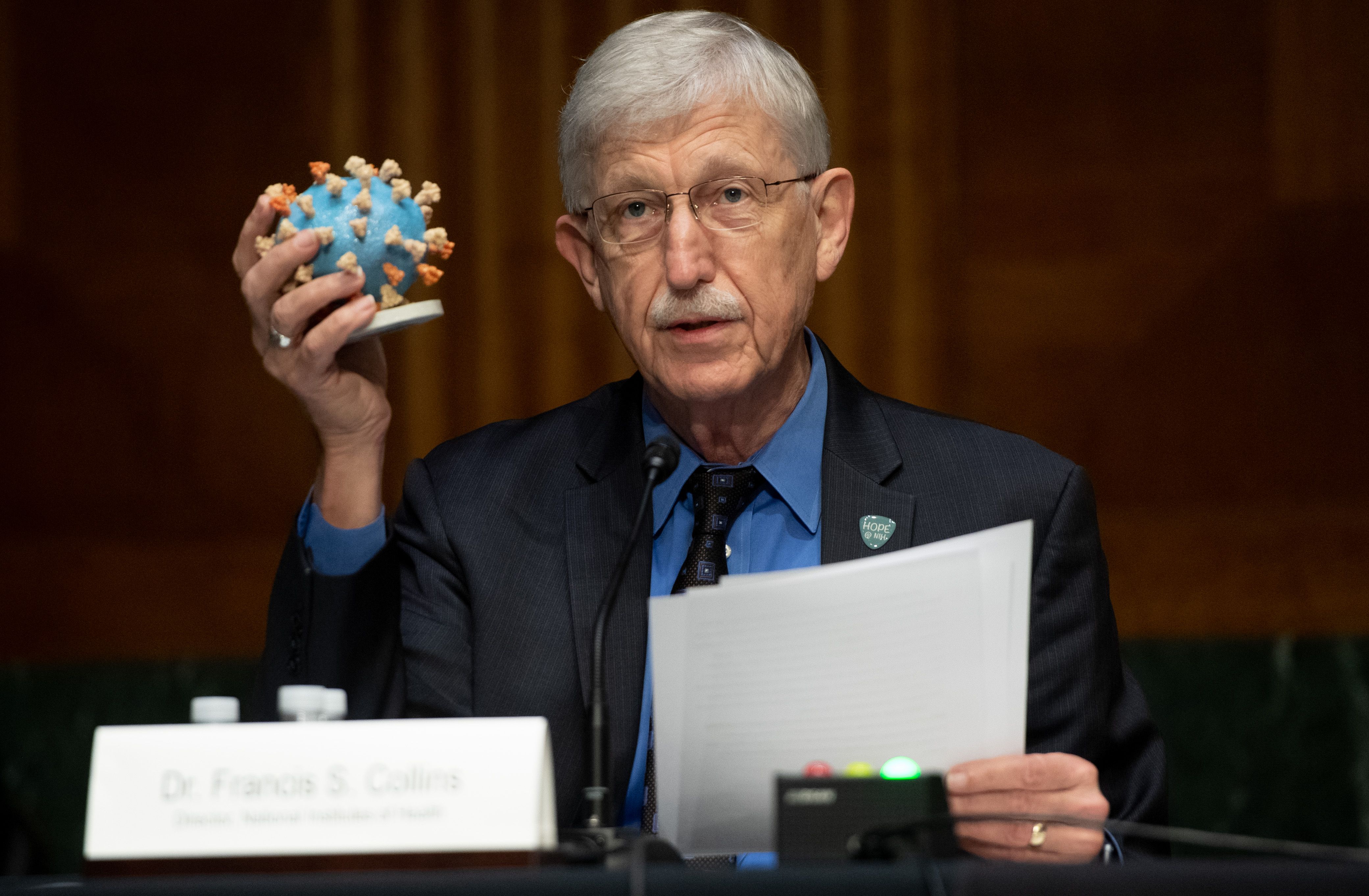 Dr. Francis Collins holds up a model of COVID-19 during a Senate hearing in 2020.