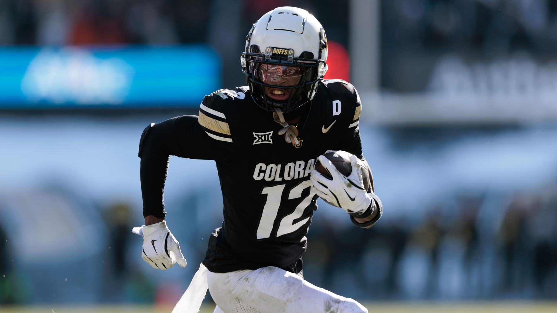 A man in a white helmet and black jersey runs with a football in his hands.