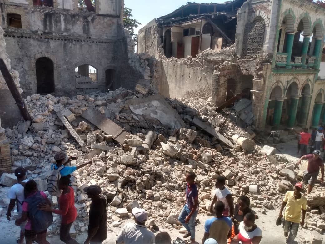 People inspect damaged buildings after a 7.2 magnitude earthquake struck Haiti on August 14