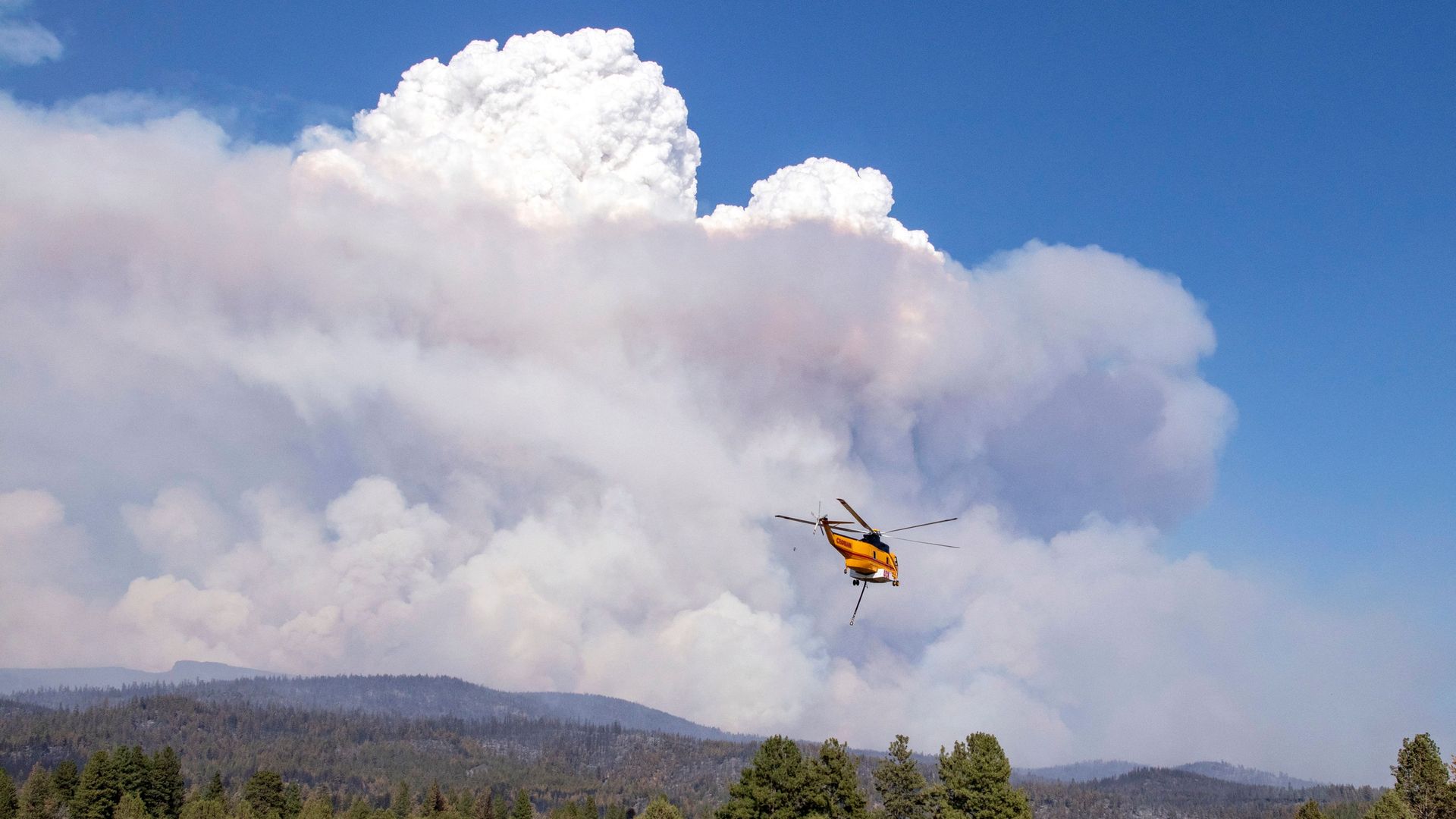 A helicopter flies with a load of water to the Bootleg Fire, 27 miles northeast of Klamath Falls, near Bly, Oregon on July 15
