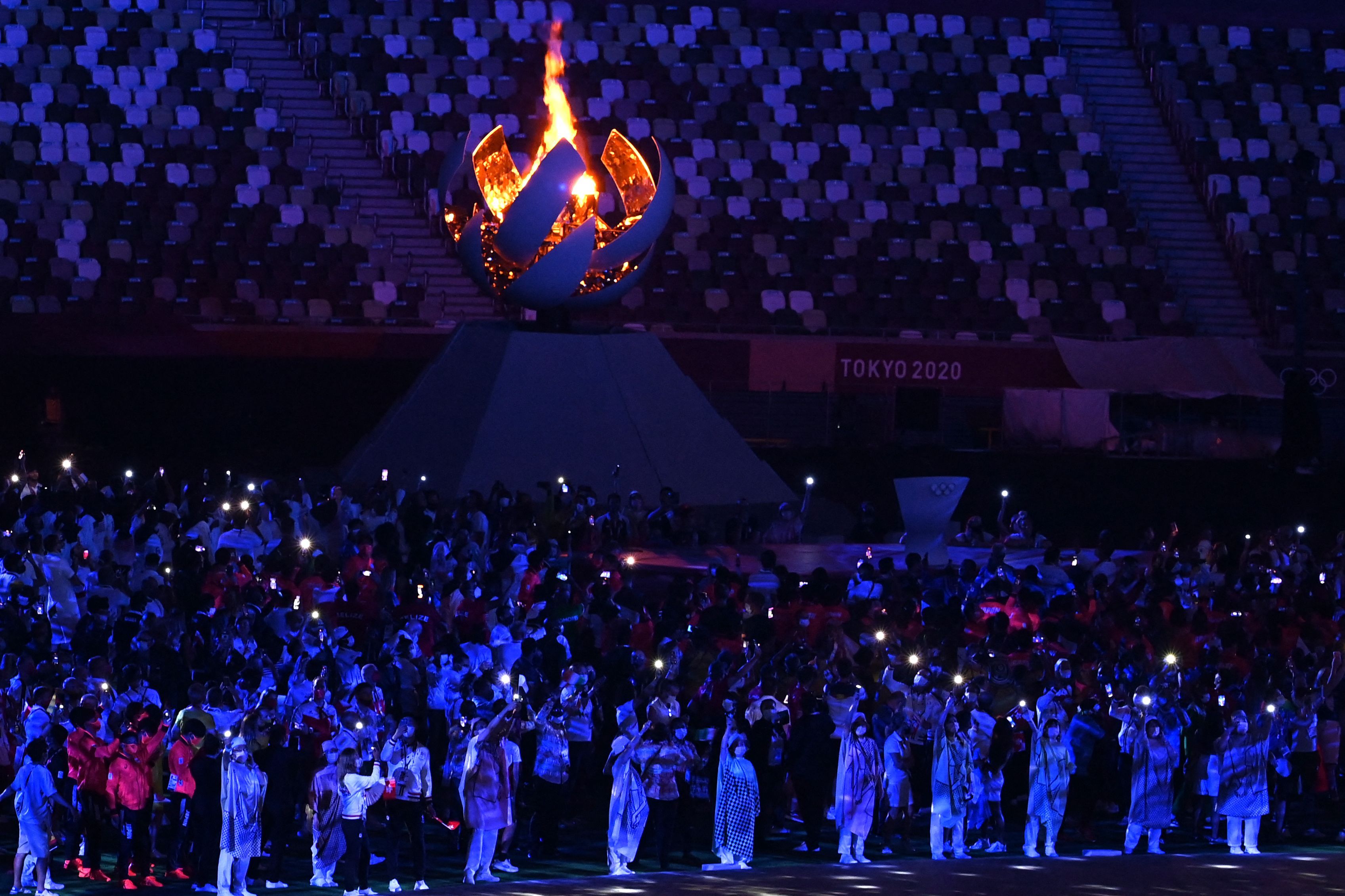 The olympic cauldron surrounded by athletes.