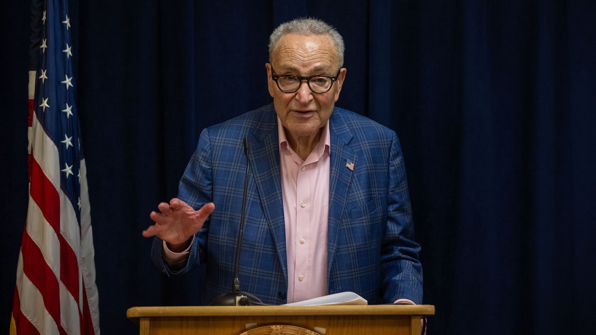 Schumer at a podium with a U.S. flag