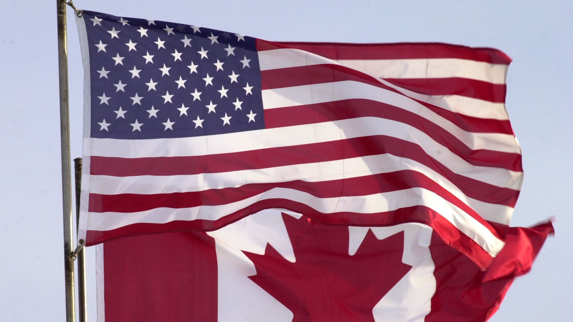 A photo of the Canadian flag flying behind the U.S. flag.