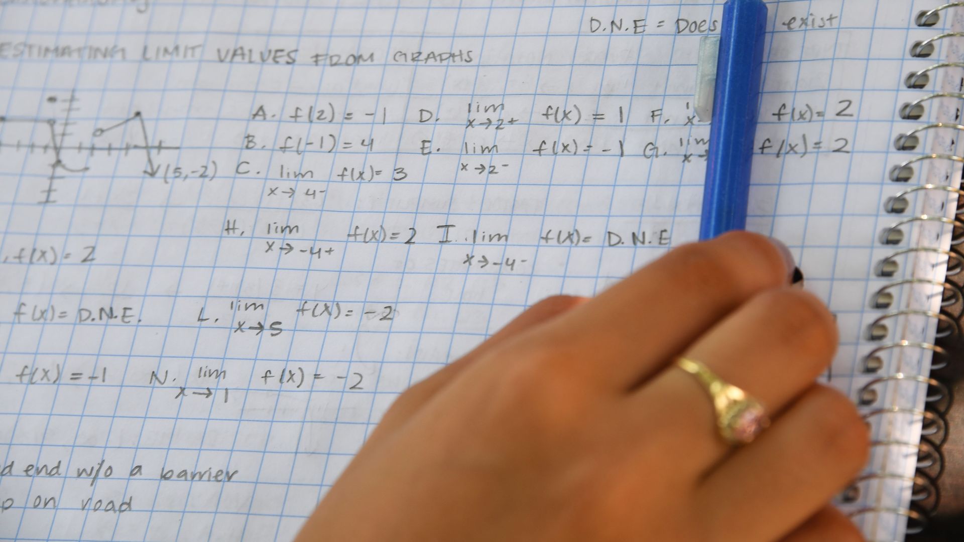 Photo of a hand holding a pencil over a notebook filled with math equations