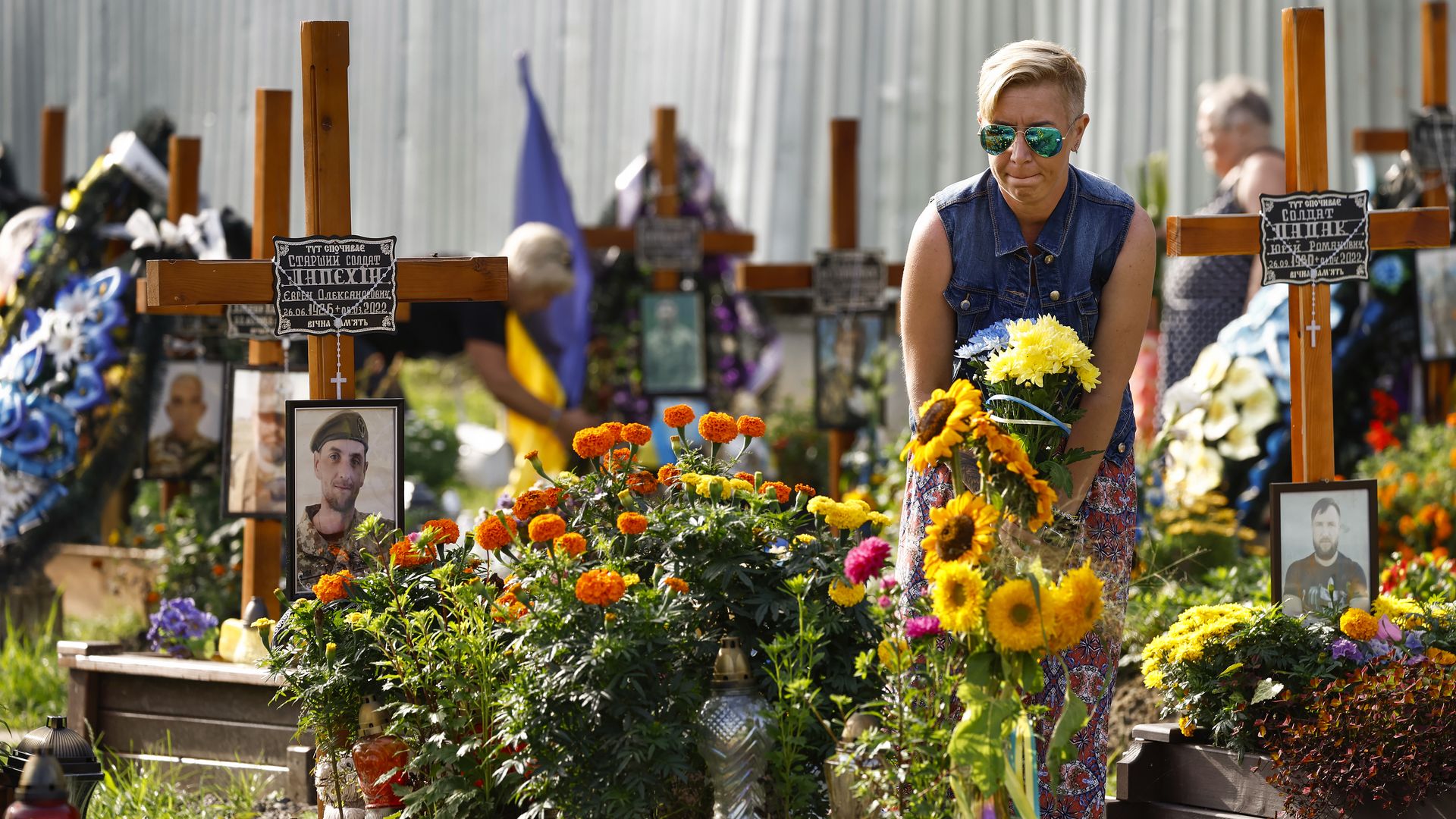 Woman by a grave decorated by flowers in Lviv