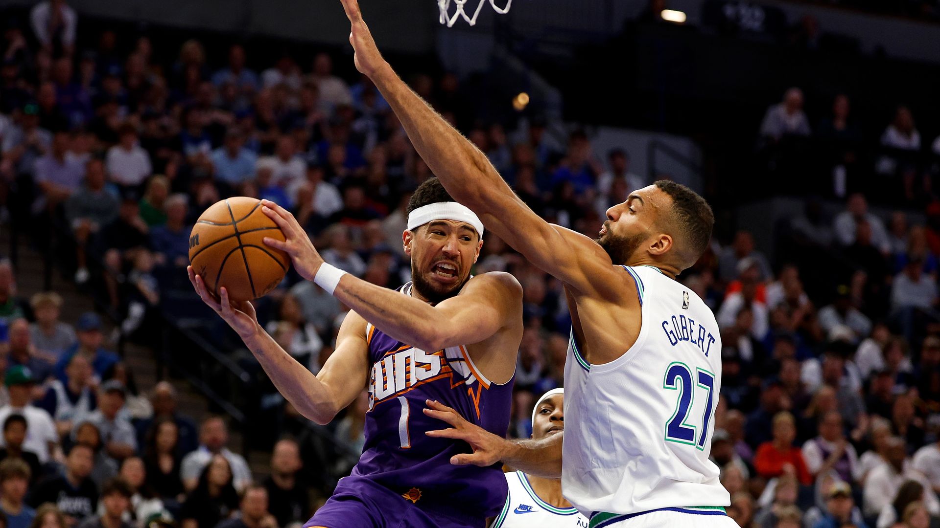 A basketball player drives for a layup against a defender.