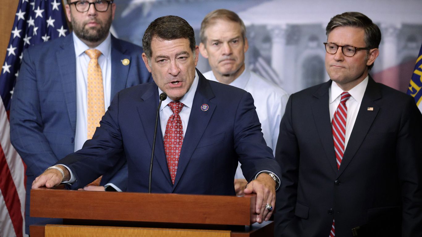 Mark Green, wearing a blue suit, speaks at a podium flanked by Mike Johnson, Jim Jordan and Jason Smith.