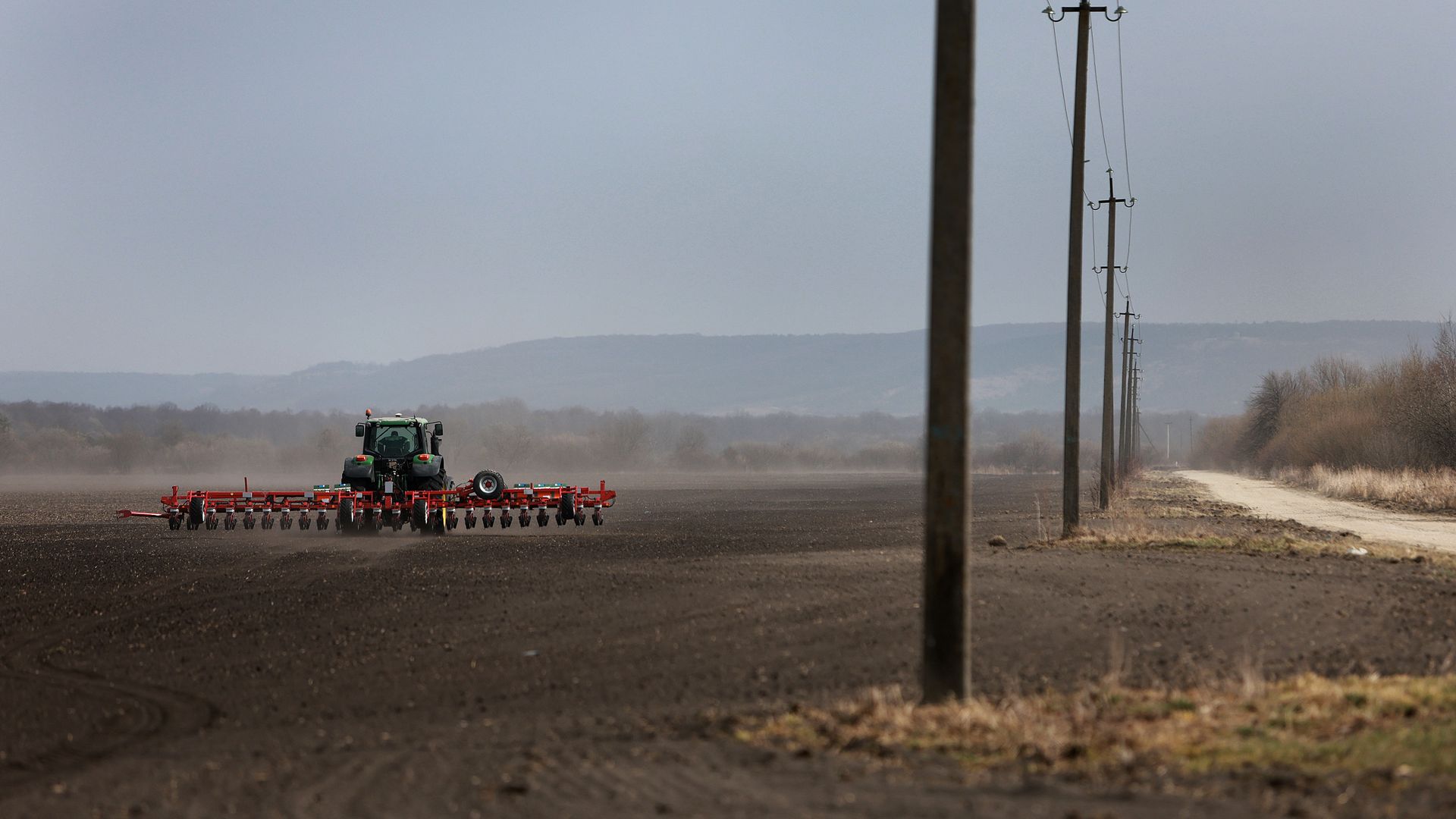: Farmer Morda Vasyl drives a tractor pulling a planter with sugar beet seeds on the Zahidnyi Bug Farm on March 26, 2022 in Humnyska, Ukraine.