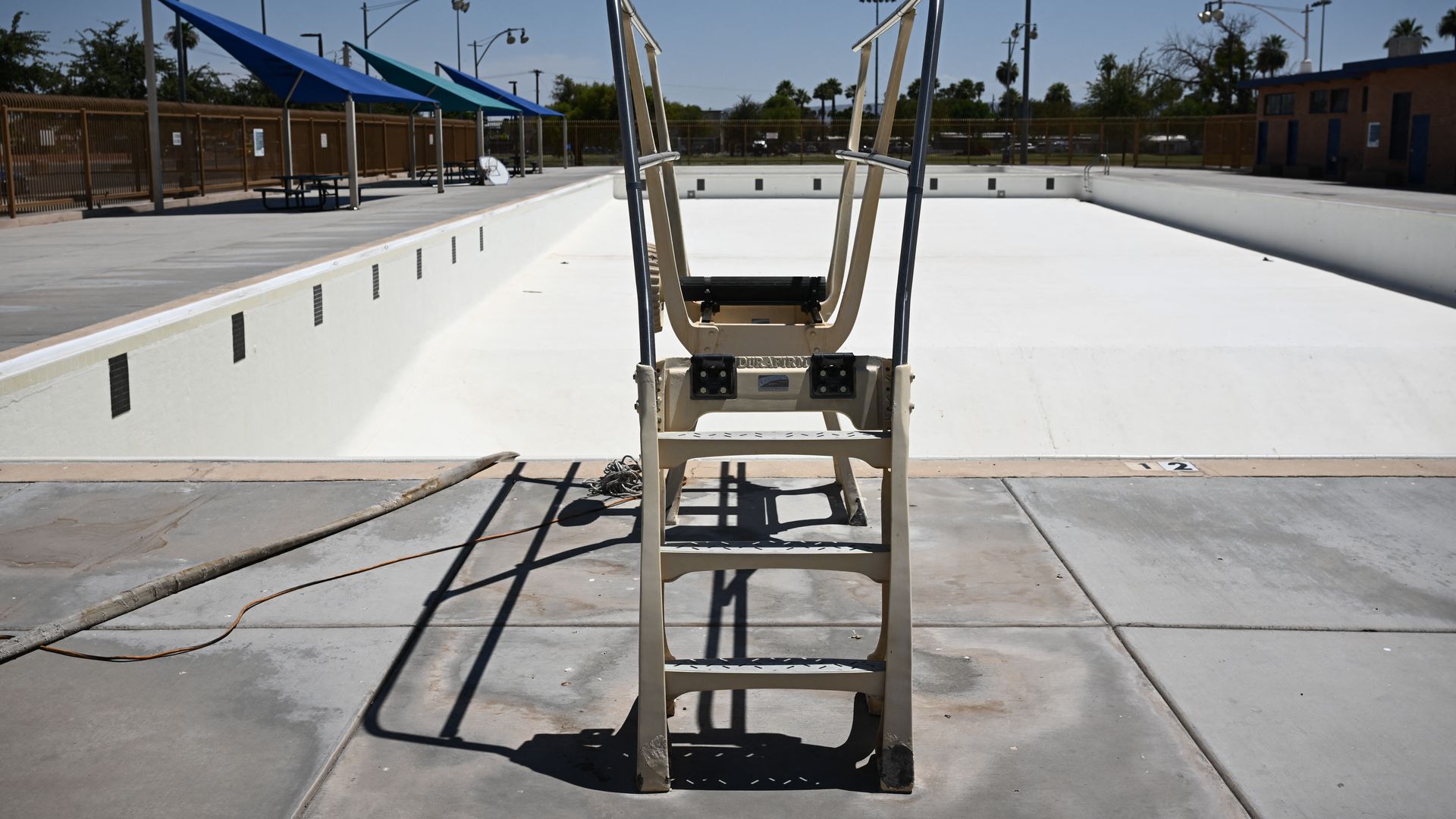 A disassembled diving board in front of a drained pool.