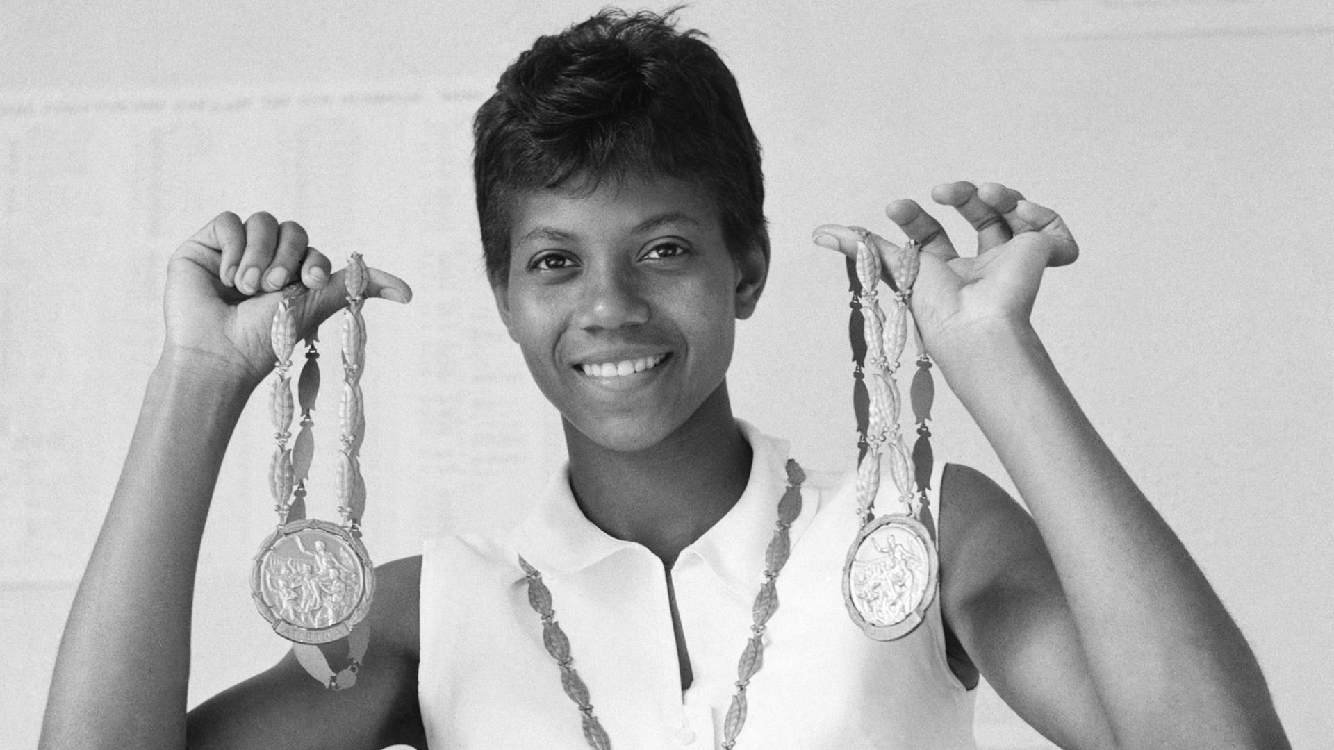 A photograph of Wilma Rudolph holding two gold medals. 