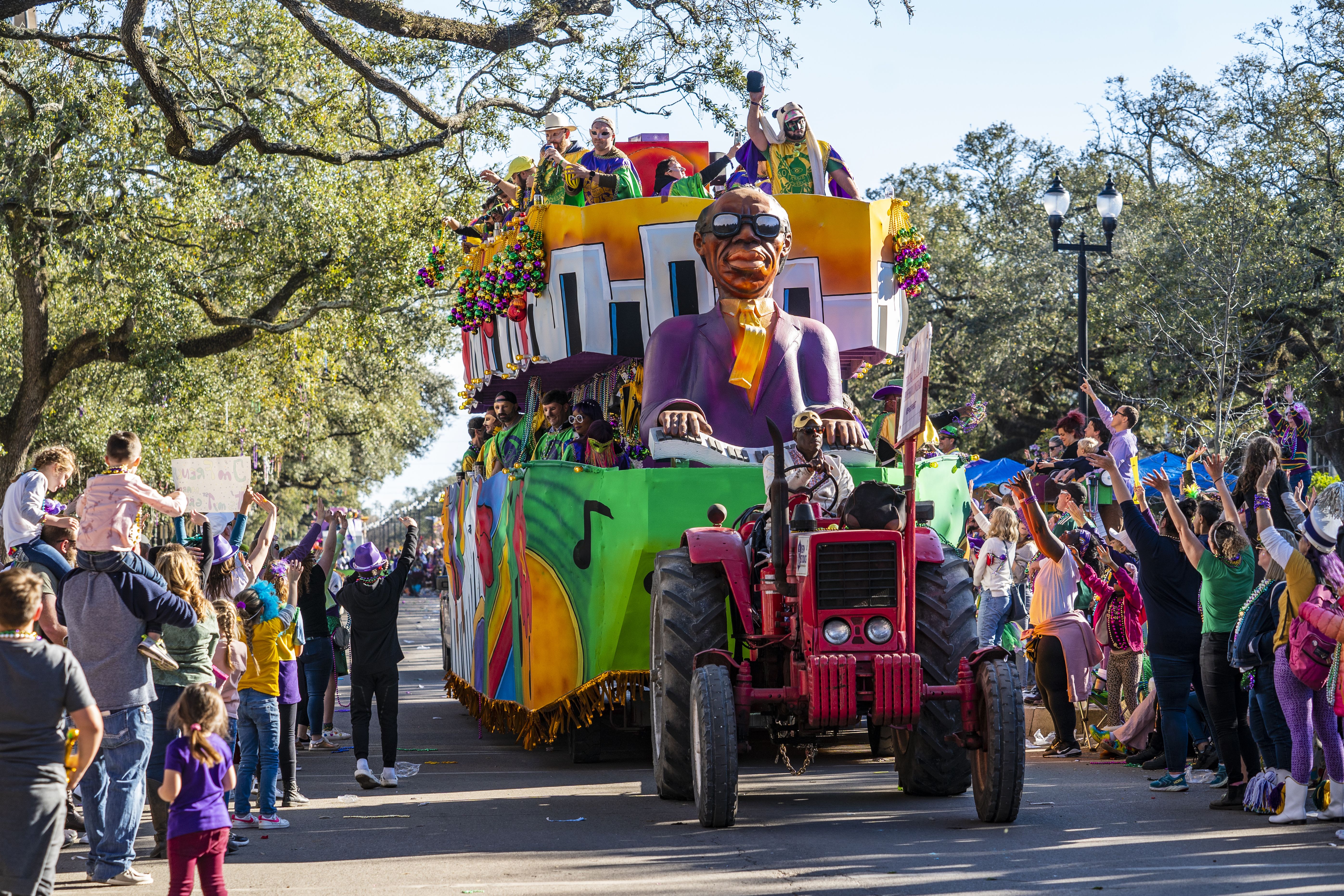 Photo shows a red tractor pulling a Mardi Gras float in New Orleans