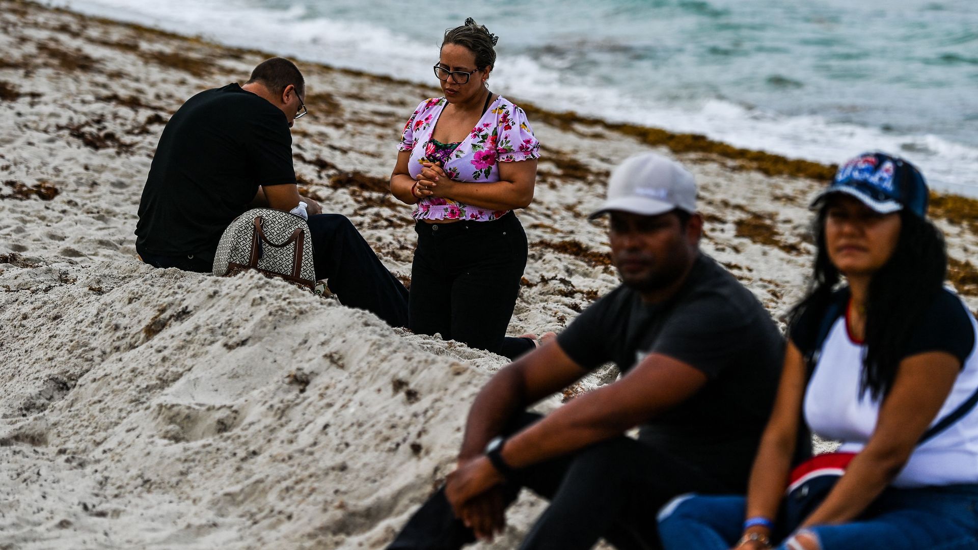 A woman prays as rescue workers search the rubble at the site of a collapsed building in Surfside, Florida.