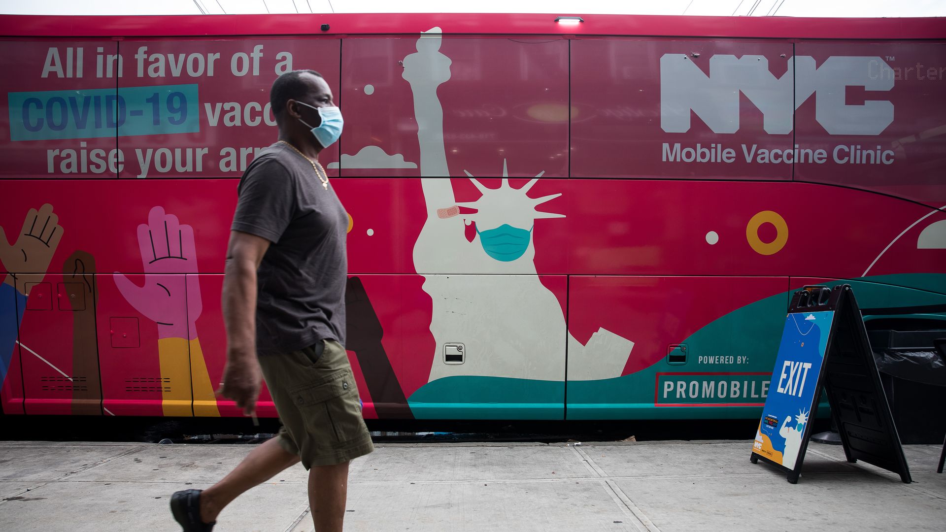 Photo of a masked person walking by a mobile vaccine clinic 