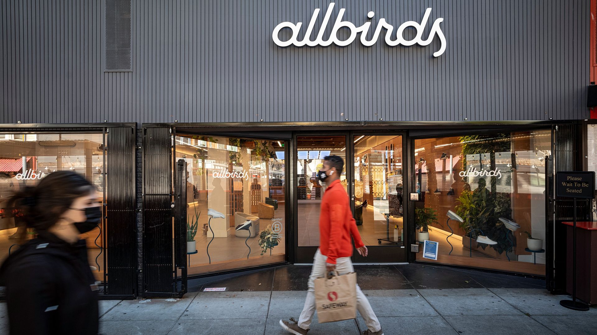 Man walking past Allbirds store wearing Allbirds shoes.