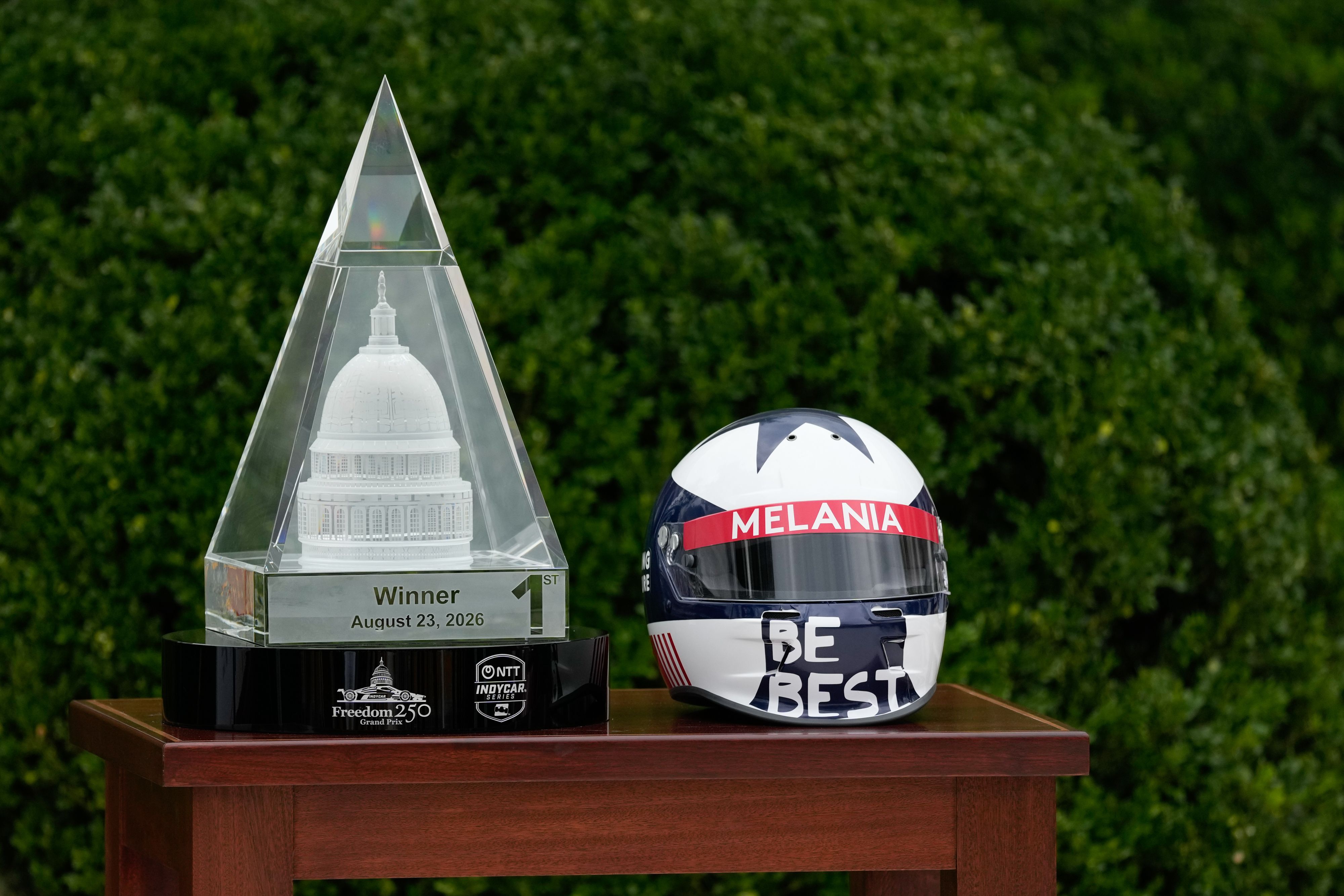 A pyramid-like trophy next to a racing helmet. 