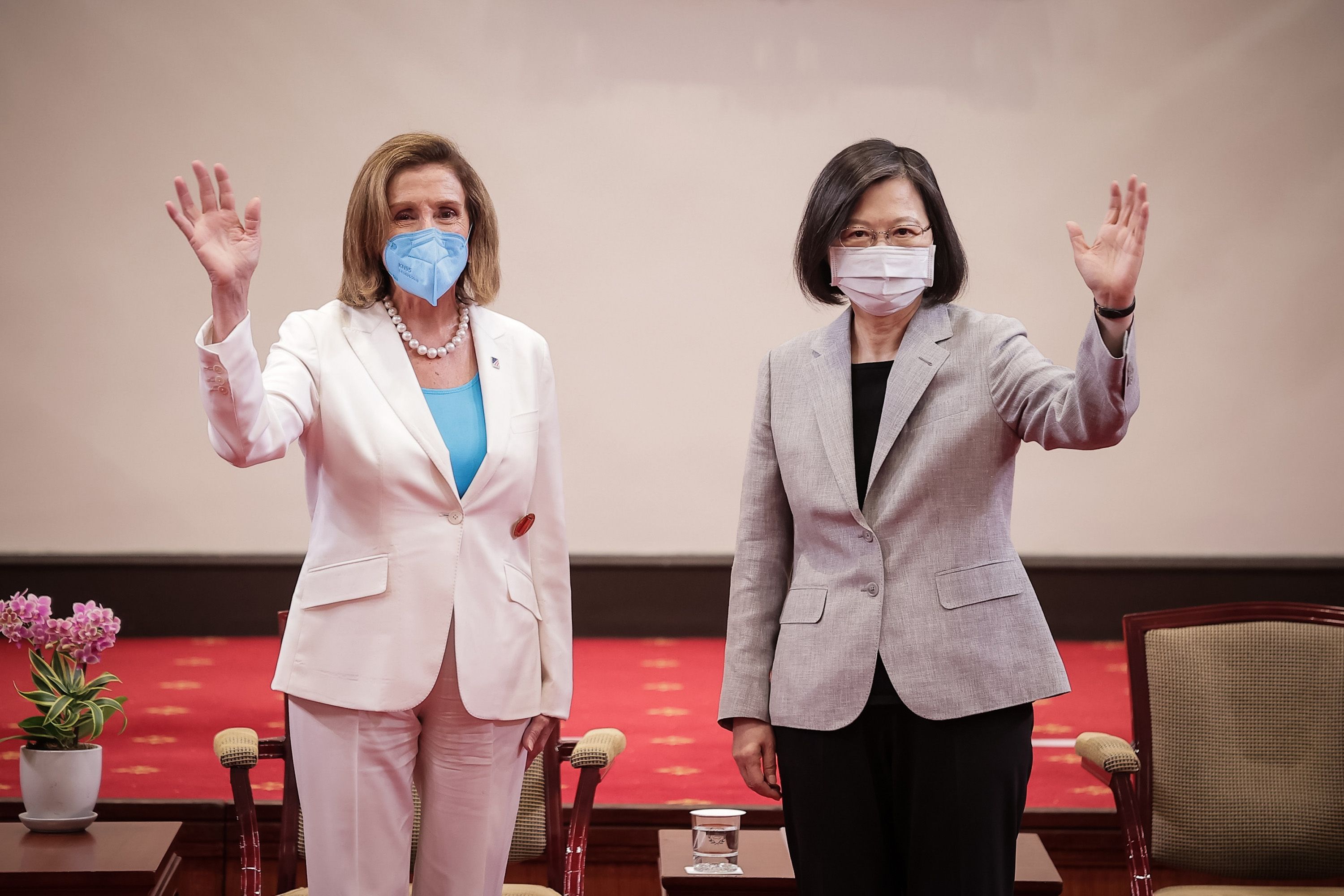 Nancy Pelosi and President Tsai Ing-wen stand side by side while waving in masks for a photo at Taiwan's presidential office during Pelosi's 2022 visit.