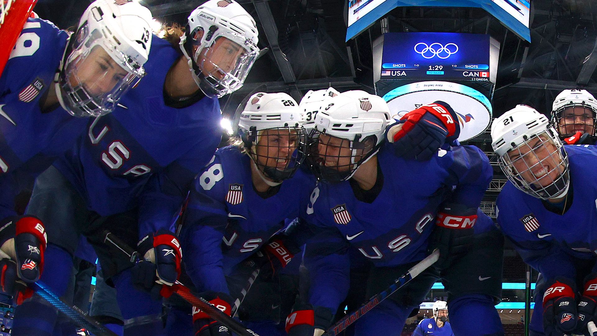Members of the U.S. Women's Hockey Team pose behind a net.