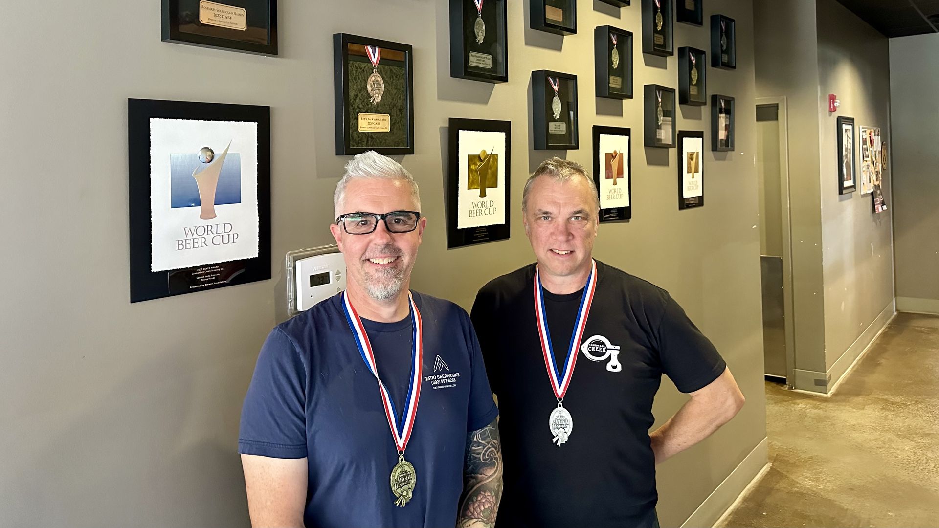 Cannonball Creek founders, Brian Hutchinson, right, Jason Stengl, left, hold their new GABF medals in front of a wall of accolades