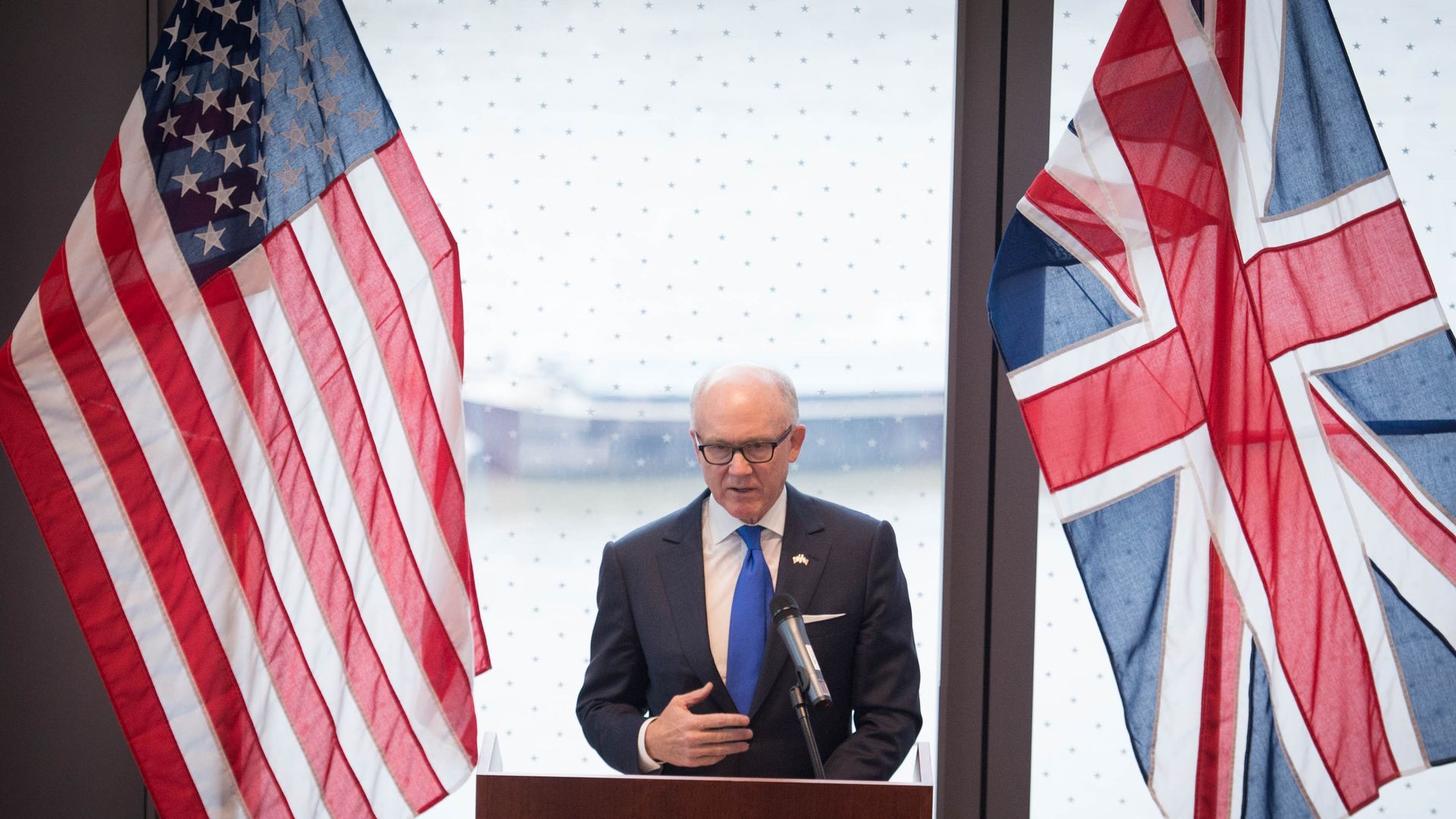 Woody Johnson in between an American and British flag